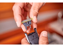 Charger l'image dans la galerie, Mains tenant une nouvelle lame de rasoir, prête à être fixée au manche du rasoir. L'arrière-plan est flou.
