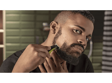 Charger l'image dans la galerie, Homme taillant sa barbe avec une tondeuse électrique, plan rapproché.
