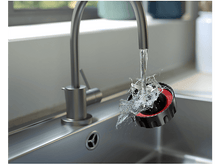 Charger l&#39;image dans la galerie, De l&#39;eau éclaboussant d&#39;un robinet sur un objet noir et rouge dans un évier.
