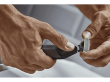 Charger l&#39;image dans la galerie, Mains tenant une tondeuse électrique noire et grise, prête à fixer une nouvelle tête.
