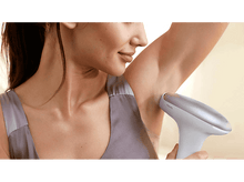 Charger l&#39;image dans la galerie, Une femme utilise un appareil d&#39;épilation sur son aisselle. L&#39;appareil est blanc et argenté.
