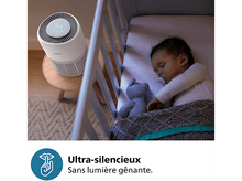 Charger l'image dans la galerie, Un bébé dort dans un berceau à côté d'un purificateur d'air sur une table en bois.
