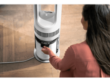 Charger l&#39;image dans la galerie, Femme ajustant le filtre d&#39;un purificateur d&#39;air Philips blanc. Le purificateur est sur un sol en bois.
