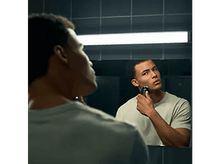 Charger l&#39;image dans la galerie, Un homme se rase le visage devant un miroir. Il regarde son reflet. L&#39;arrière-plan est une salle de bain.
