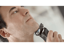 Charger l&#39;image dans la galerie, Un homme se rasant le visage avec un rasoir électrique.
