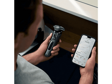 Charger l&#39;image dans la galerie, Un homme tenant un rasoir électrique noir et un téléphone avec données de rasage.
