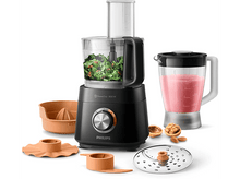Charger l&#39;image dans la galerie, Un robot culinaire Philips noir avec accessoires et ingrédients comme des noix et des légumes verts.
