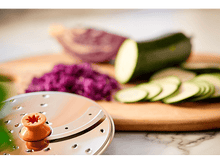 Charger l&#39;image dans la galerie, Légumes : courgettes tranchées, chou rouge haché et une trancheuse à légumes sur bois.
