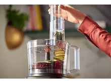 Charger l&#39;image dans la galerie, Un robot culinaire est utilisé avec des légumes à l&#39;intérieur et une main qui ajoute.
