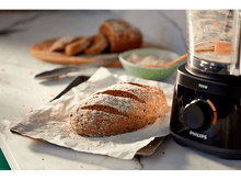 Charger l&#39;image dans la galerie, Un pain sur du papier sulfurisé avec un robot culinaire et du pain tranché sur une planche à découper.
