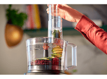 Charger l&#39;image dans la galerie, Un robot culinaire avec des légumes à l&#39;intérieur et une main tenant le couvercle supérieur.
