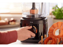 Charger l&#39;image dans la galerie, La main d&#39;une personne tourne le cadran d&#39;un robot culinaire noir. Des accessoires orange sont à proximité.
