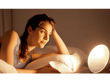 Charger l&#39;image dans la galerie, Une femme allongée dans son lit, regardant une lumière avec l&#39;heure 07h05, sur fond blanc.
