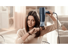 Charger l&#39;image dans la galerie, Femme se brossant les cheveux avec une brosse tout en utilisant un sèche-cheveux.
