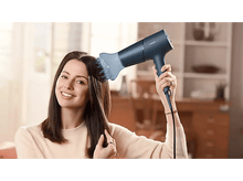 Charger l&#39;image dans la galerie, Femme utilisant un sèche-cheveux bleu foncé sur ses cheveux foncés, souriant.
