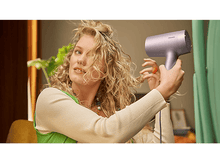 Charger l&#39;image dans la galerie, Une femme utilise un sèche-cheveux, regardant ses cheveux et un miroir.
