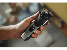 Charger l&#39;image dans la galerie, Personne tenant un rasoir Philips noir et argent. Le rasoir est allumé.
