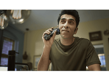 Charger l&#39;image dans la galerie, Homme se rasant avec un rasoir Philips noir et argent, regardant vers le haut avec concentration.
