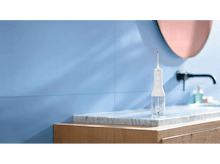 Charger l&#39;image dans la galerie, Un hydropulseur blanc et transparent est sur une étagère en marbre. Mur et miroir bleus en arrière-plan.
