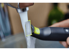Charger l&#39;image dans la galerie, Un rasoir électrique noir et jaune sous l&#39;eau courante. La lame est mise au point.
