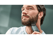 Charger l&#39;image dans la galerie, Un homme barbu utilise une tondeuse à barbe. Plan rapproché.
