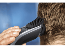 Charger l'image dans la galerie, Une personne utilise une tondeuse à cheveux pour couper les cheveux à l'arrière de la tête de quelqu'un.
