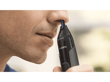 Charger l&#39;image dans la galerie, Un homme coupe les poils du nez avec une tondeuse noire. La tondeuse est tenue près de sa narine.
