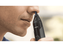 Charger l&#39;image dans la galerie, Un homme utilise un coupe-nez Philips. L&#39;appareil est noir et le nez de l&#39;homme est mis au point.
