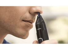 Charger l&#39;image dans la galerie, Un homme se coupe les poils du nez avec une tondeuse noire.
