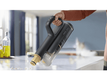 Charger l'image dans la galerie, Main tenant un aspirateur à main noir et doré sur une surface en marbre.

