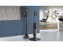 Charger l'image dans la galerie, Deux aspirateurs noirs et dorés, un debout, un au sol, dans une pièce.
