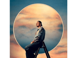 Un homme assis sur une échelle, dos au spectateur, avec un grand cadre circulaire en arrière-plan.