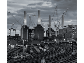 Scène industrielle avec centrale, grues, voies ferrées et un cochon volant.