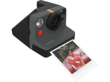 Charger l&#39;image dans la galerie, Appareil photo Polaroid avec photo éjectée, personne en arrière-plan.
