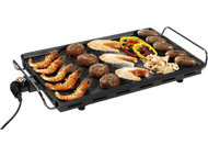 Gril avec crevettes, poisson, saucisses et légumes. Surface noire avec poignée.