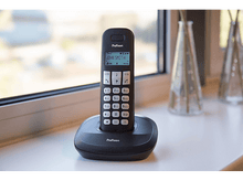 Charger l&#39;image dans la galerie, Un téléphone sans fil noir sur son socle avec l&#39;écran affichant &#39;John Smith&#39;.
