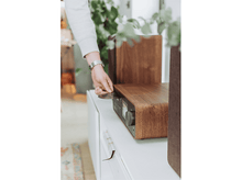 Charger l'image dans la galerie, Une personne insérant un CD dans un système audio en bois, avec des enceintes en arrière-plan.
