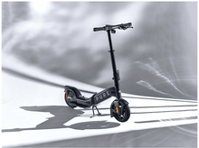 Charger l&#39;image dans la galerie, Une trottinette gris foncé sur fond blanc avec effets de lumière.
