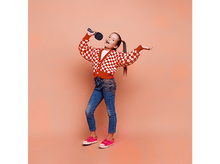 Charger l&#39;image dans la galerie, Fille chantant dans un microphone noir, portant un pull à carreaux rouge et un jean.
