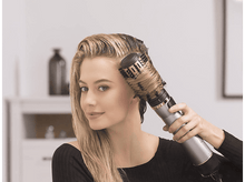 Charger l'image dans la galerie, Une femme utilise une brosse sèche-cheveux sur ses cheveux mouillés. Elle sourit.
