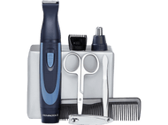 Un kit de toilettage avec tondeuse, ciseaux, peigne et autres outils sur une surface claire.