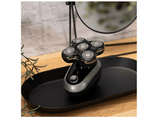 Charger l&#39;image dans la galerie, Rasoir électrique sur un plateau noir, avec un miroir. Le rasoir a cinq têtes.
