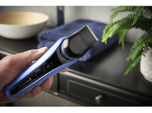 Charger l&#39;image dans la galerie, Homme tenant une tondeuse à cheveux Remington bleue et noire, près d&#39;articles de salle de bain.
