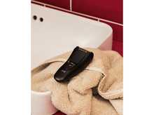 Charger l&#39;image dans la galerie, Un rasoir électrique noir Remington F2 repose sur une serviette beige dans un évier blanc.
