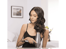 Charger l&#39;image dans la galerie, Femme se coiffant avec un sèche-cheveux et un diffuseur devant un miroir.
