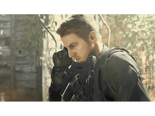 Charger l&#39;image dans la galerie, Homme en équipement tactique noir, regardant vers le bas, fond de feuillage.
