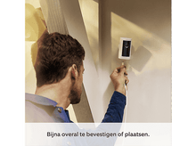 Charger l&#39;image dans la galerie, Un homme installe une caméra Ring blanche et noire sur un mur blanc. La caméra est sans fil.
