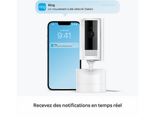 Charger l&#39;image dans la galerie, Un smartphone avec une notification de l&#39;application Ring à côté d&#39;une caméra de sécurité Ring blanche.
