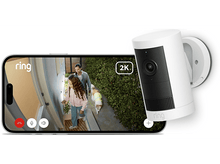 Charger l&#39;image dans la galerie, Une caméra de sécurité Ring à côté d&#39;un téléphone montrant une famille et un chien, avec une étiquette 2K.
