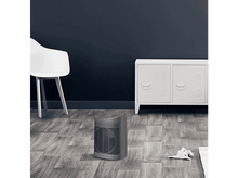 Charger l&#39;image dans la galerie, Un radiateur électrique gris sur un sol en bois contre un mur bleu foncé. Chaise blanche.
